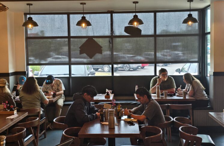 Groups of customers sit at tables in a restaurant.