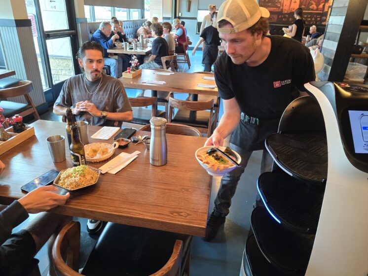 a waiter removes a plate from a robot server