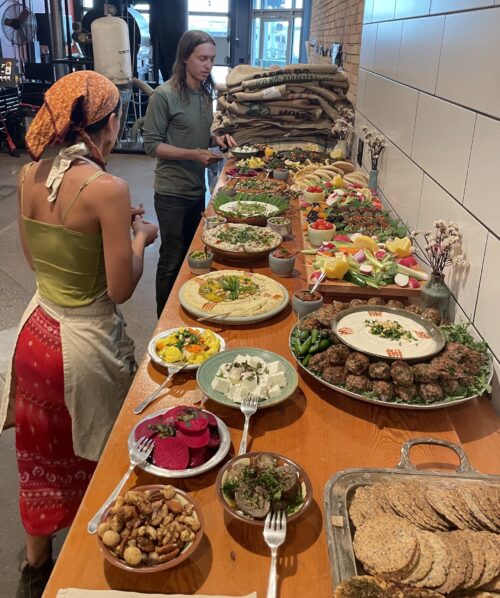 Two people with a long table of colorful food